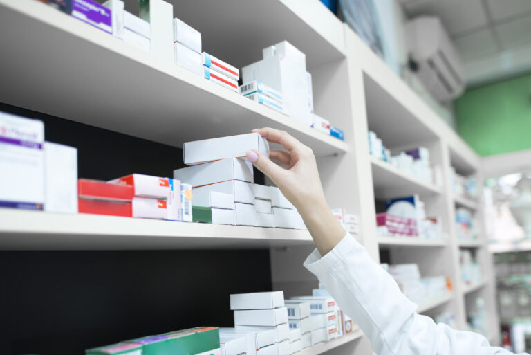 Closeup view of pharmacist hand taking medicine box from the shelf in drug store